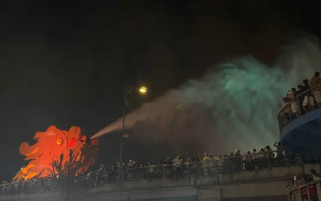 橋の龍の像が水を噴き出し見物客が並ぶ夜景